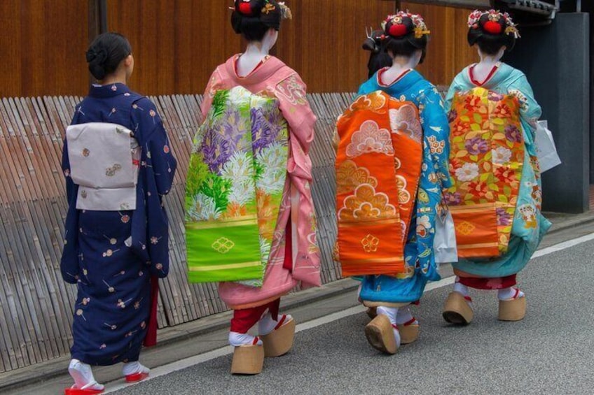 Drei Personen in traditionellen japanischen Kimonos gehen auf einer Straße. 4