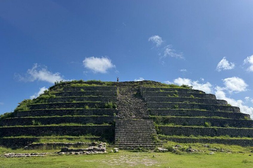 Una gran estructura piramidal escalonada con una escalera que lleva a la cima. 2