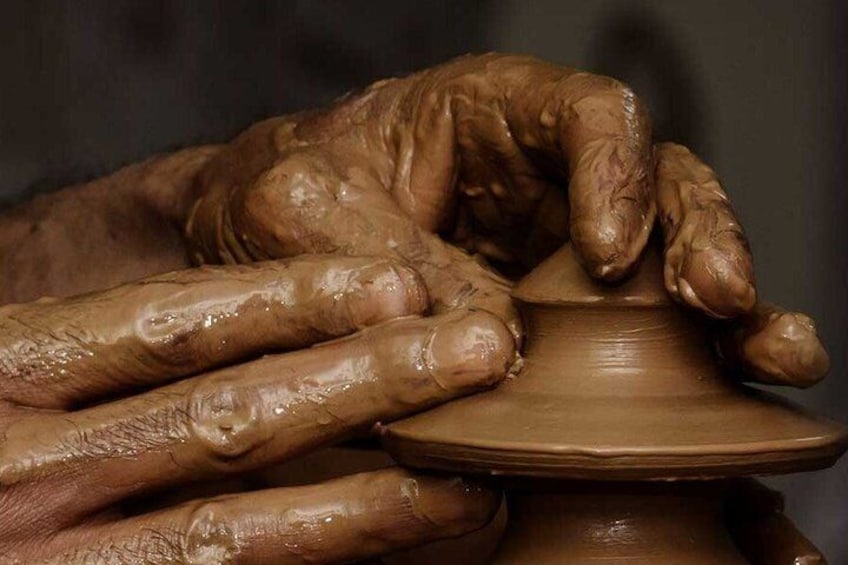 Hands shaping a clay pot on a wheel. 5