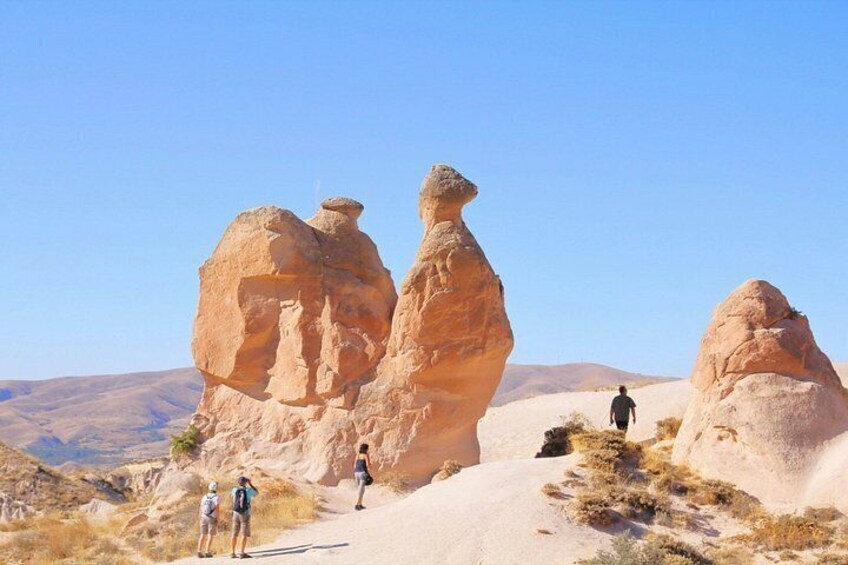A desert landscape with rock formations and hikers. 2