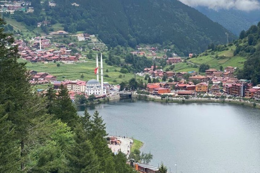 A lake surrounded by buildings, a mosque with two minarets, and a red flag. 1