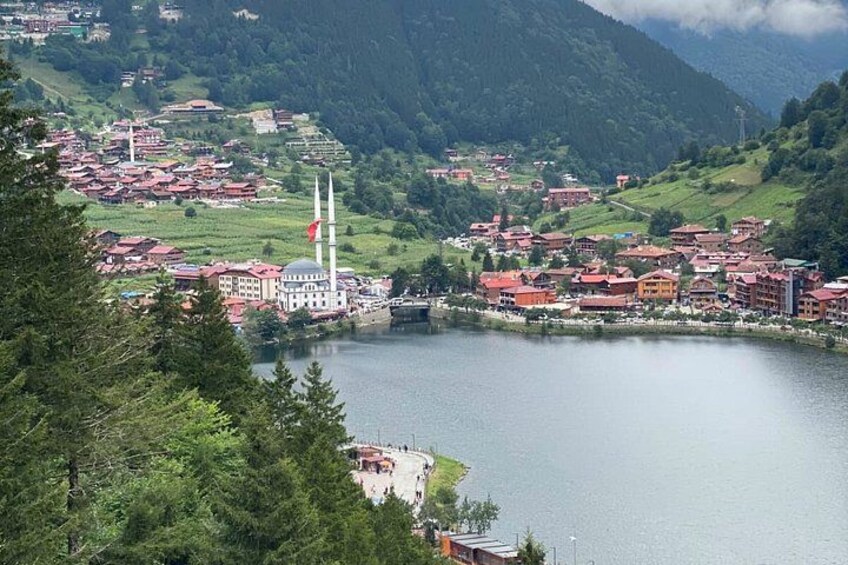 A lake surrounded by buildings, a mosque with two minarets, and a red flag. 1