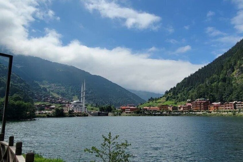 A lake with a mosque and buildings on the shore, surrounded by mountains. 3