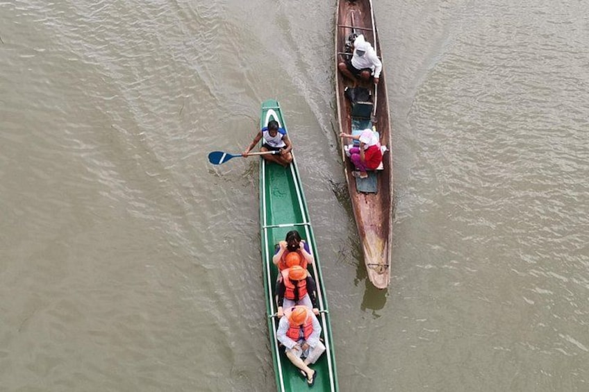 Deux canoës sur une rivière, l’une verte et l’autre marron, avec des personnes qui les manient à l’aide de pagaies. 1