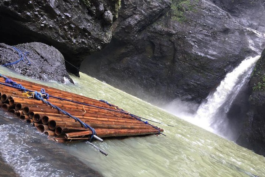 A wooden raft on a river with a waterfall in the background. 1