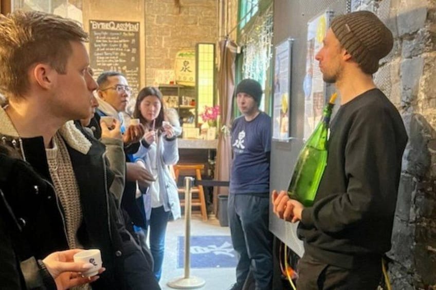 A group of people standing in a cafe with a brick wall and menu board in the background. 5