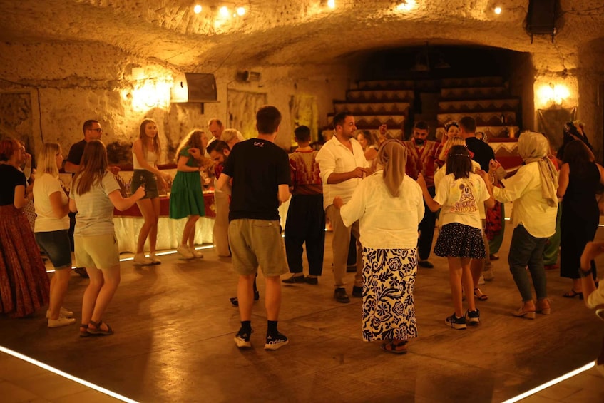 A group of people dancing in a dimly lit room with stone walls and wooden floors. 4
