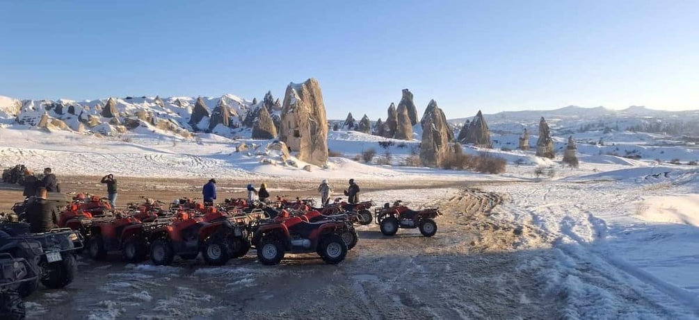 A group of people on ATVs in a snowy landscape with distinctive rock formations. 1