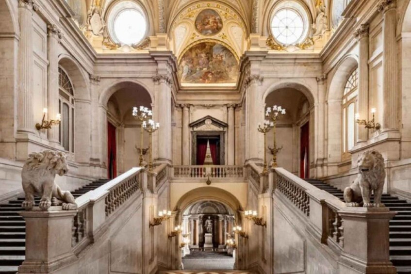 A grand staircase with ornate railings and lion statues, leading to a balustrade and a red curtain. 4
