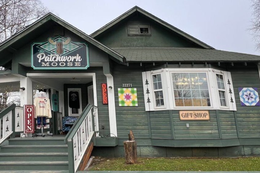A green building with a sign reading 'The Patchwork Moose Gift Shop.' 3