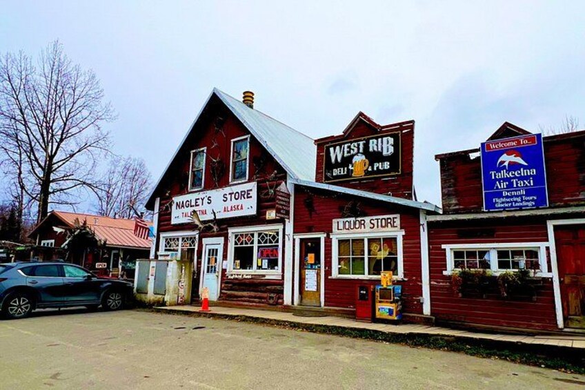 A red building with signs for Nagley's Store, West Rib, and a Liquor Store. 3
