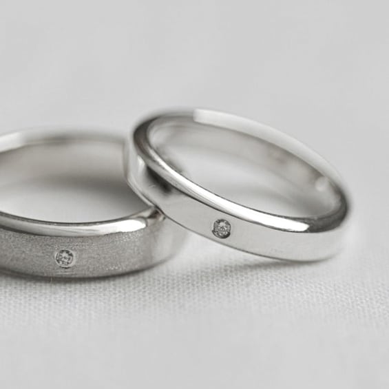 Two silver rings with a diamond on each band. 4