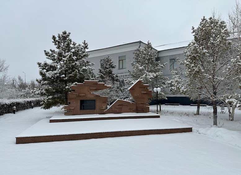A snow-covered sculpture in a park with a building in the background. 3