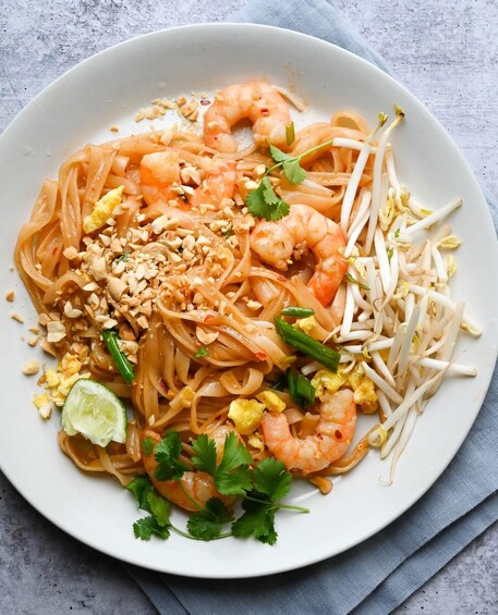 A plate of Pad Thai noodles with shrimp, bean sprouts, peanuts, lime, and cilantro. 5