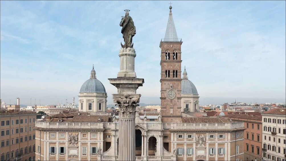 A historic building with a statue, a clock tower, and a dome. 1