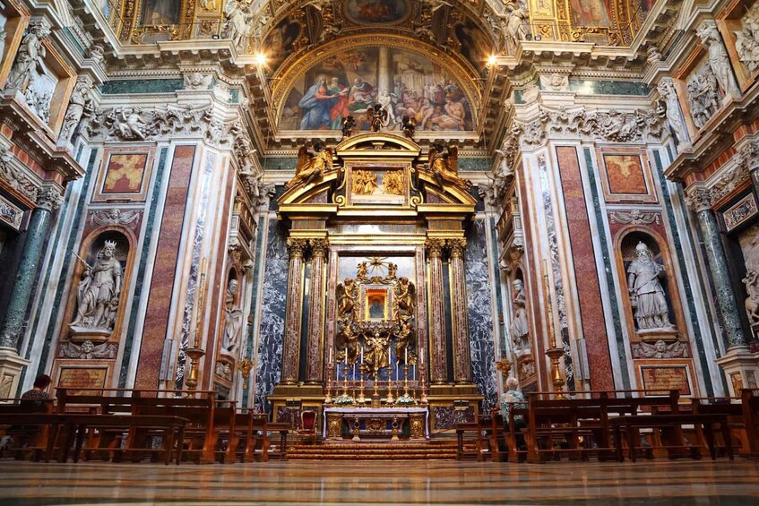 An ornate church interior with a central altar, statues, and a detailed ceiling fresco. 3