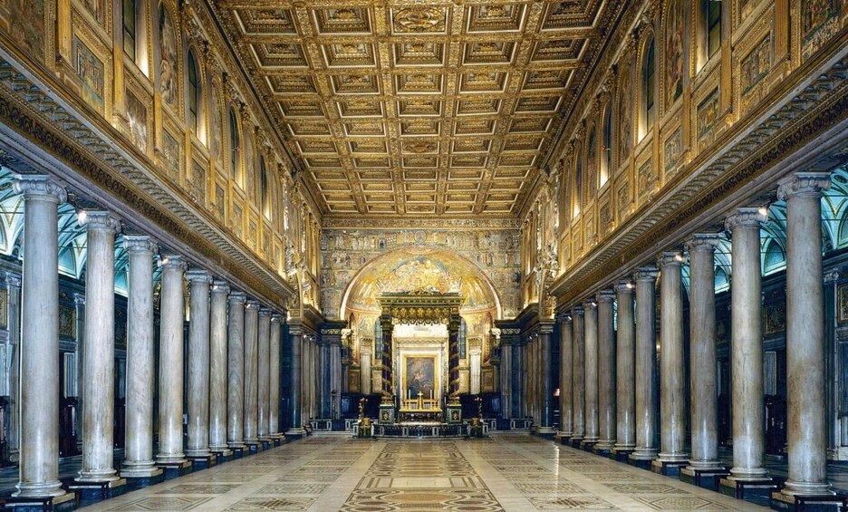A grand hall with a high ceiling, ornate columns, and a central altar. 5