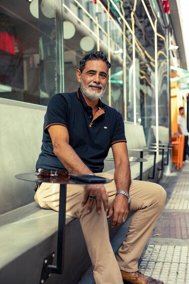 A man sitting on a bench with a table in front of him, in an outdoor seating area with a modern design. 5