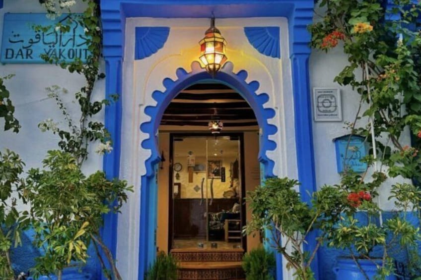 A building with a blue facade, a decorative archway, and a sign that reads 'DAR YAKOUT.' 1