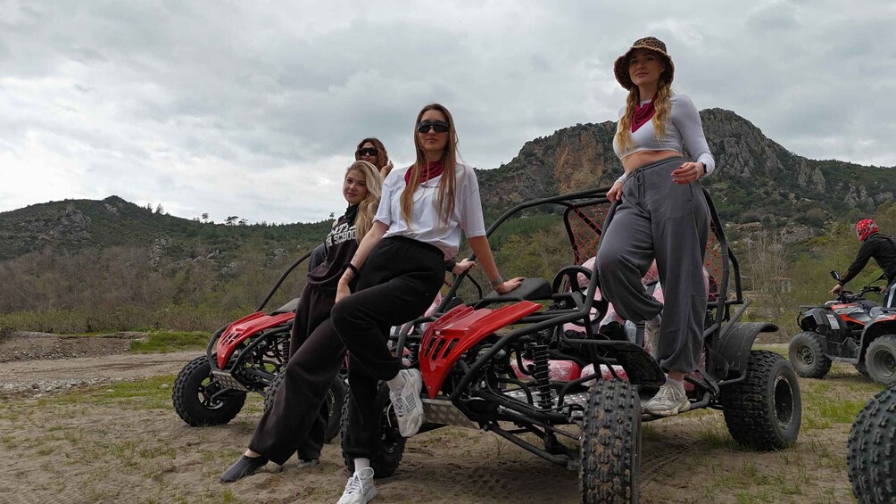 Three people on quad bikes in a mountainous area with rocky terrain and sparse vegetation. 1