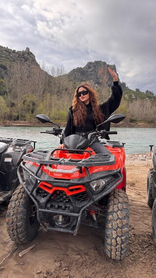 A person on a red ATV with a mountainous landscape in the background. 1