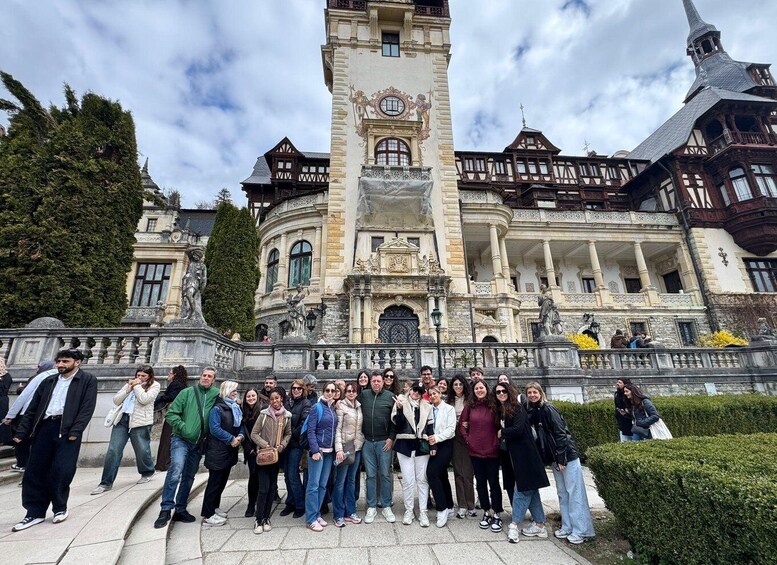 A group of people standing in front of a historic building with a prominent tower and ornate architecture. 5