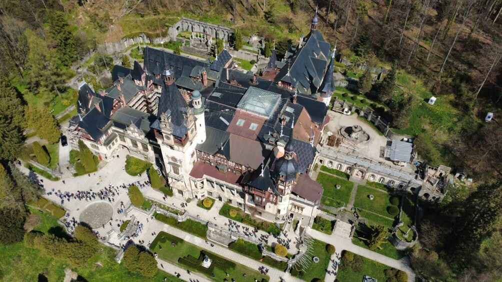 An aerial view of a historic castle complex with multiple towers, a central courtyard, and surrounding gardens. 3