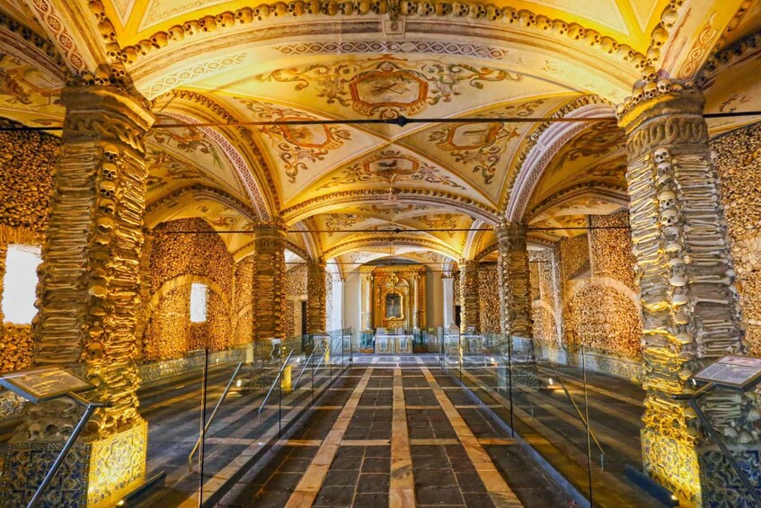 An ornate hall with intricate ceiling designs, stone columns, and a tiled floor. 4