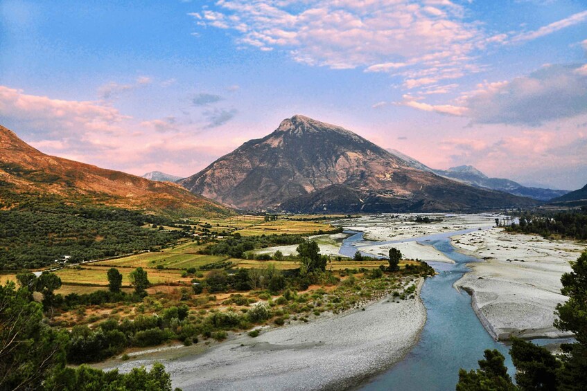 A mountainous landscape with a river, fields, and a clear sky. 2