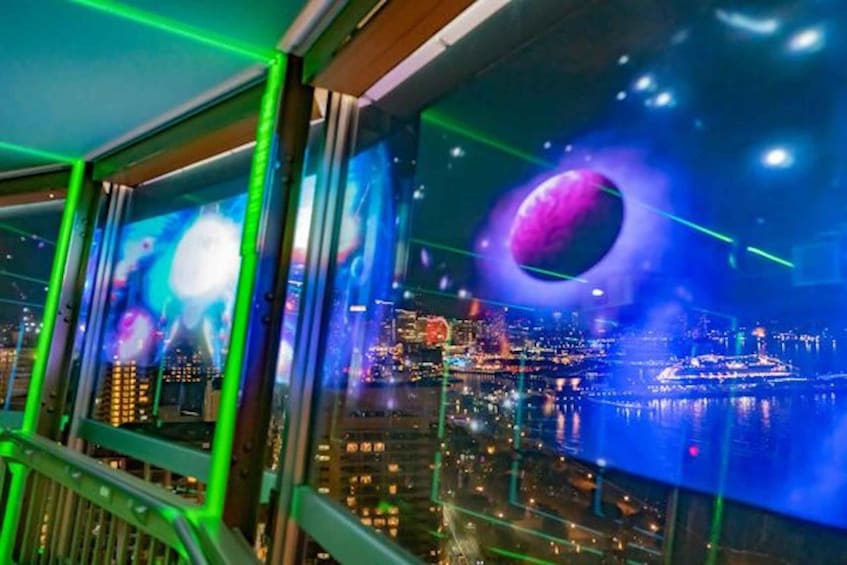 A cityscape with illuminated buildings and a large circular structure by the water. 2