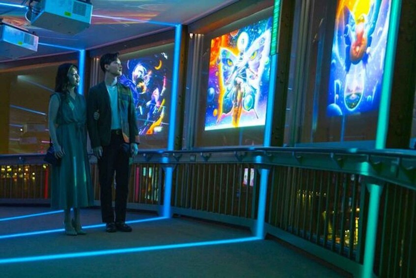 A couple standing in a brightly lit corridor with colorful murals on the walls. 4