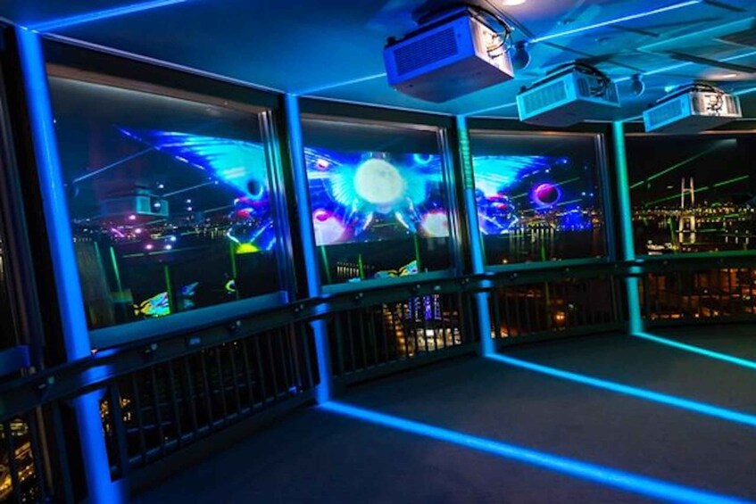 A room with multiple screens displaying vibrant cityscapes, illuminated by blue lighting. 5