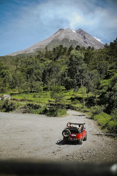A red off-road vehicle on a dirt path with a mountain in the background. 4