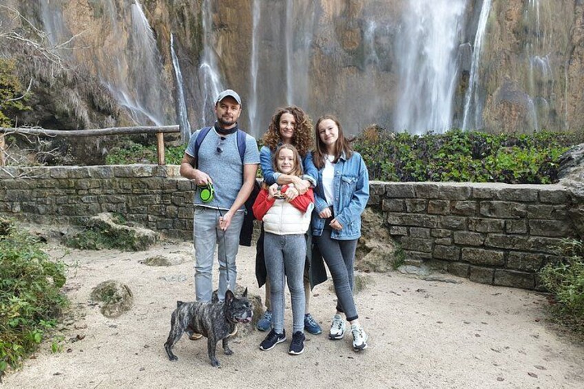 Une famille avec un chien devant une cascade. 1