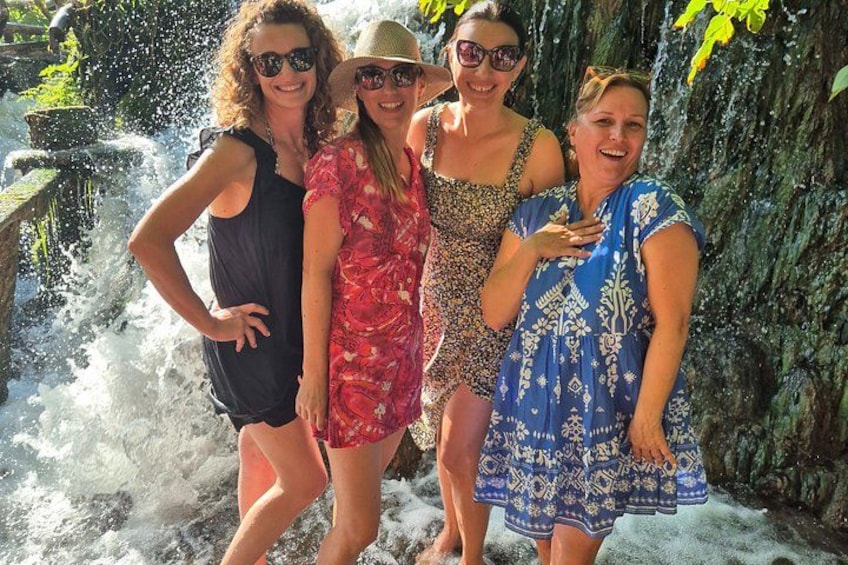 Four people standing by a waterfall with a rocky background. 2