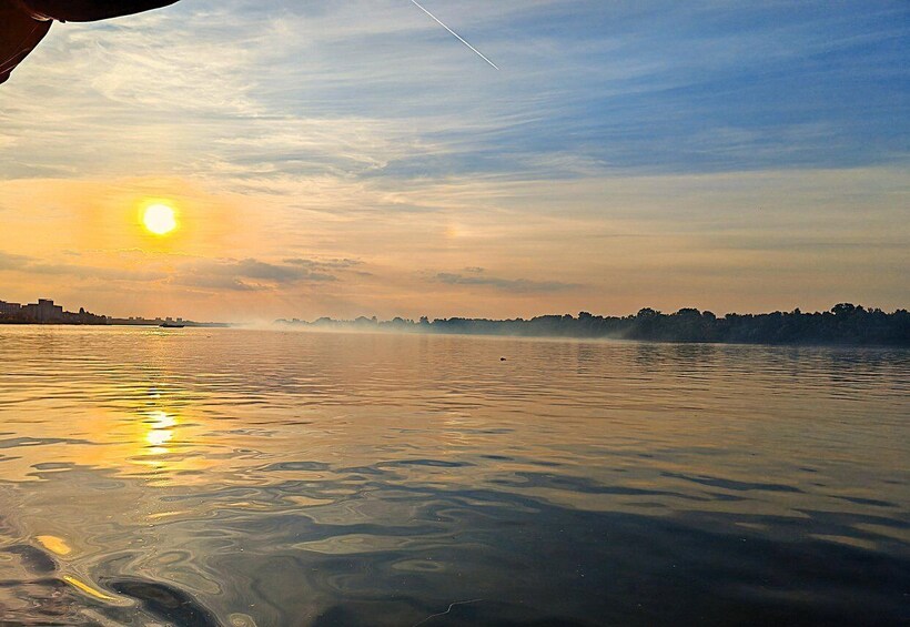 A sunset over a calm river with a city skyline in the distance. 1