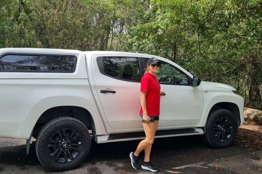 A white pickup truck parked on a road with trees in the background. 1