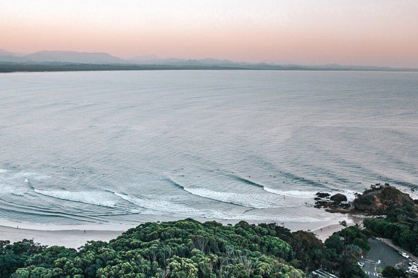 A coastal landscape with waves, a sandy beach, and dense green foliage. 2