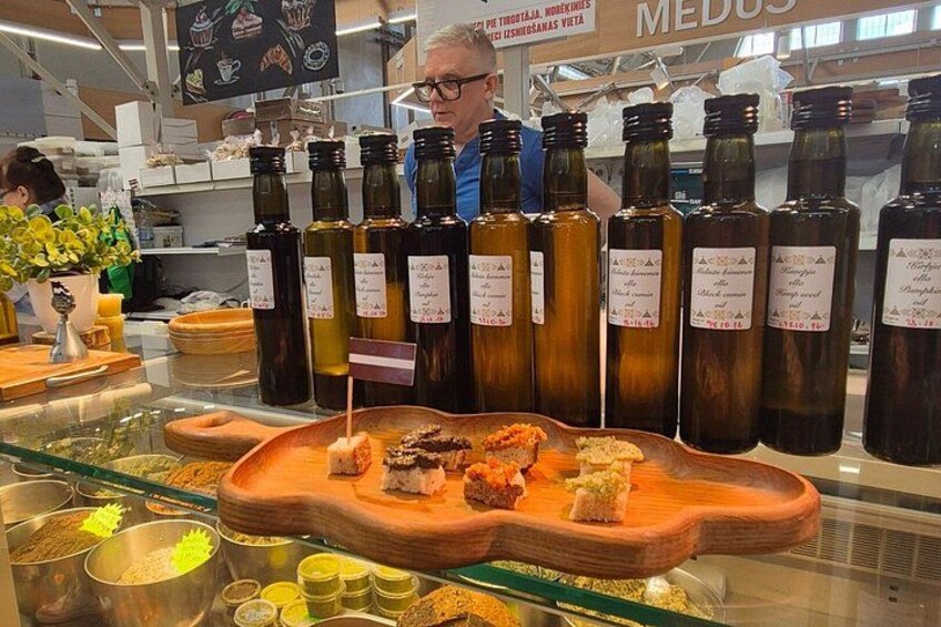 Een presentatie van olijfolafels met etiketten, een houten dienblad met etenswaren en een persoon op de achtergrond. 1