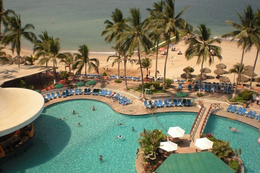 Ein Pool mit Schwimmenden, umgeben von Palmen und Liegestühlen. 2