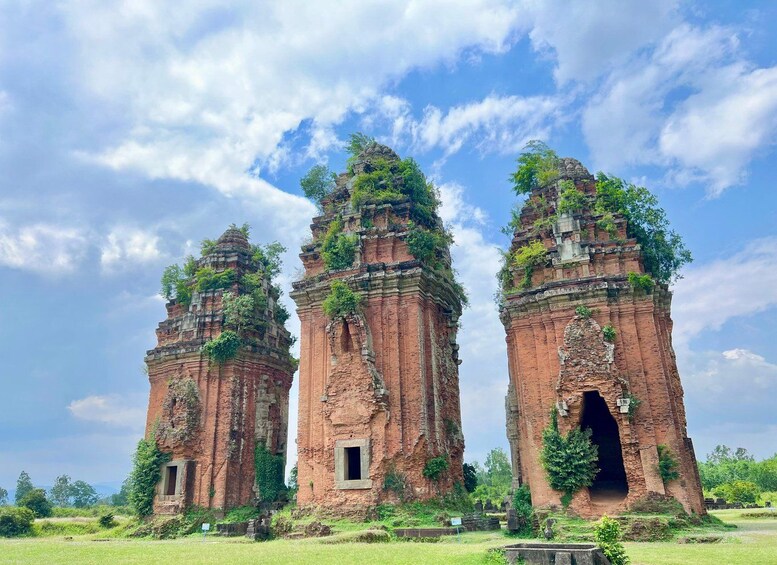 Three ancient brick towers with overgrown vegetation, set against a clear sky. 5