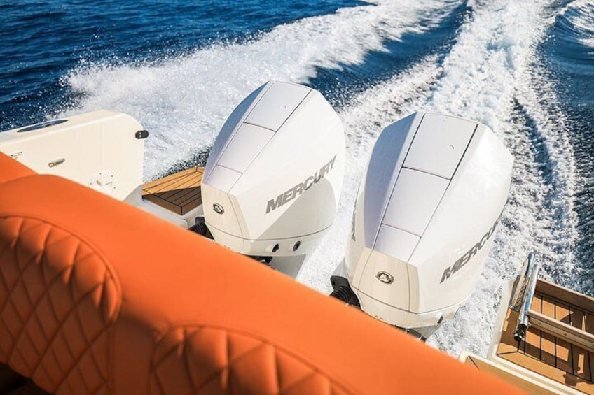 A boat with two Mercury outboard motors and an orange interior. 2