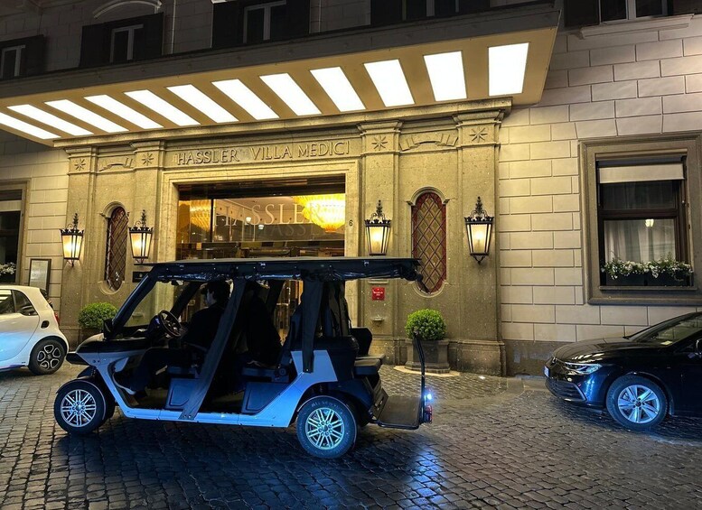 A building with 'HASSLER VILLA MEDICI' signage, a golf cart, and two parked cars. 3