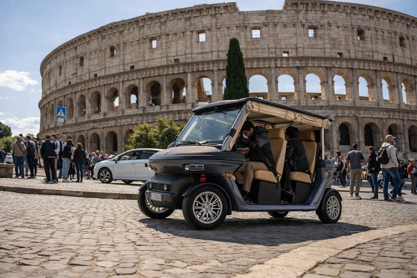 A golf cart in front of the Colosseum with tourists in the background. 1