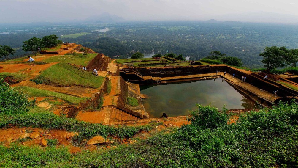 Ancient ruins with a large water body, terraced fields, and a distant view of a valley. 5