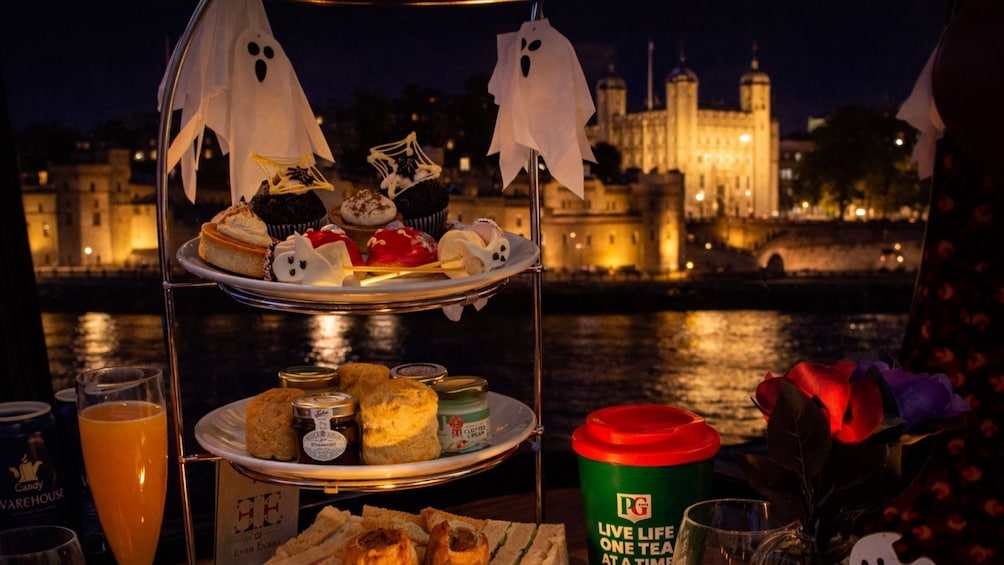 A dessert trolley with ghost-shaped decorations, a green cup with PG logo, and a cityscape with a castle in the background. 1