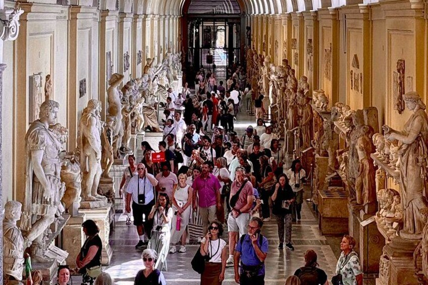 Un couloir de musée où l’on peut admirer de nombreuses statues et où se promènent des visiteurs. 2