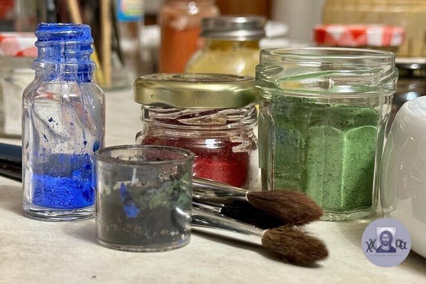 Various glass jars containing colored powders, a paintbrush, and a small metal container. 4