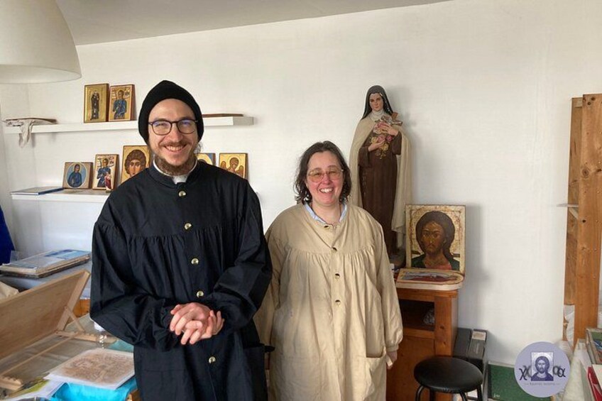 To personer står i et rum med religiøse ikoner og malerier på væggen. 2