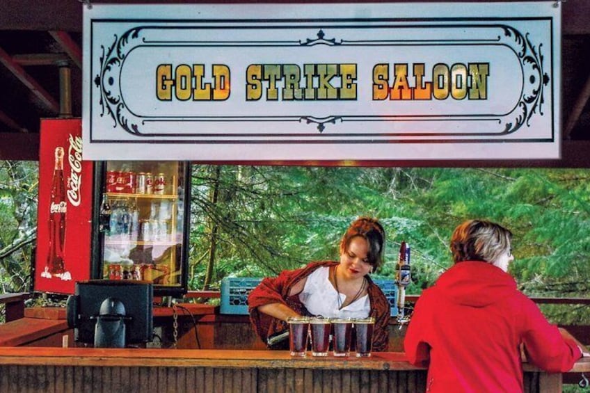 Un bar appelé « Gold Strike Saloon », avec un réfrigérateur Coca-Cola et une personne portant une veste rouge. 5